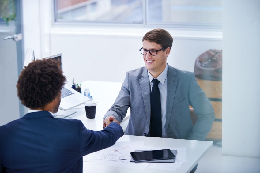 two men shaking hands over a desk