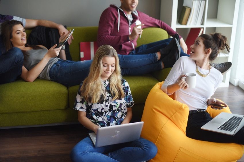 Teens relaxing on couch and beanbag with laptops