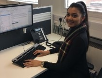 Vanessa working on a computer at a desk with a headset on